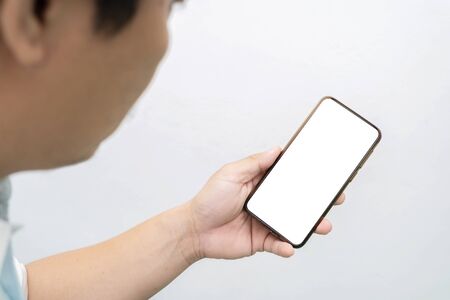 A man's hand holding a black smartphone, There is someone in the foreground. Gray isolated backgroundの写真素材