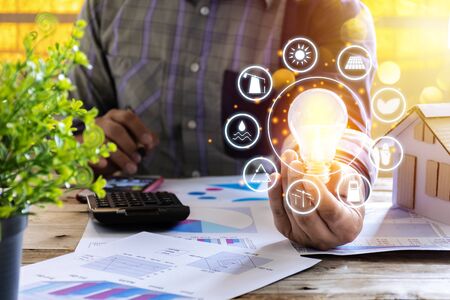 Businessmen calculate electricity bills using a calculator, graph, document. energy resources icon. Earth day. Energy saving concept, Renewable energy and energy sources of the worldの写真素材