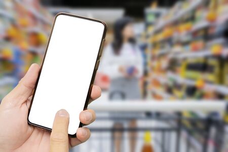 A man's hand holding a black smartphone, Touch screen smartphone in a hand. Women are shopping in supermarkets. Select the product you wantの写真素材