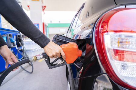 Refuel cars at the fuel pump. The driver hands, refuel and pump the car's gasoline with fuel at the...