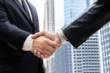 Success and Happiness concept, business man handshake at city outside office, Closeup businessmen shaking hands on background modern office corporate buildingsの写真素材