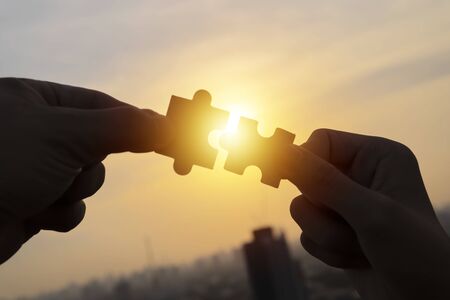 Closeup hand of businessman connecting jigsaw puzzle with sunlight effect, Business solutions, success and strategy conceptの写真素材