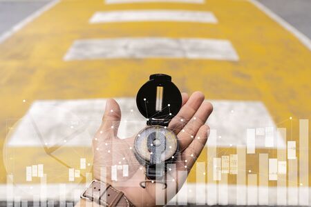 Finding goals, business investment guidelines concept. The compass rests on his hand and is walking across the crosswalk, Graph chartの写真素材