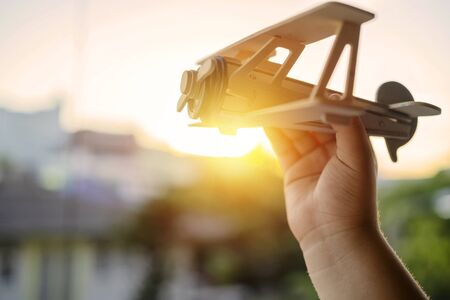 Hands of children holding a toy plane and have dreams wants to be a pilot. Toy balsa wood airplane in the sky, Independence in learning and adventure conceptの写真素材