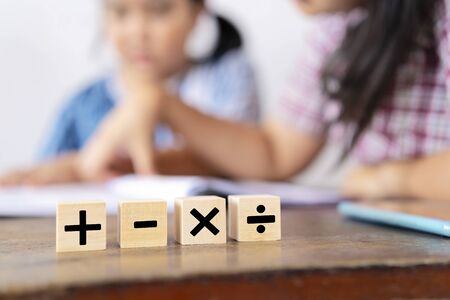 The teacher is teaching an Asian girl. They are learning math. Mathematical signs, addition, subtraction, multiplication, and divisionの写真素材