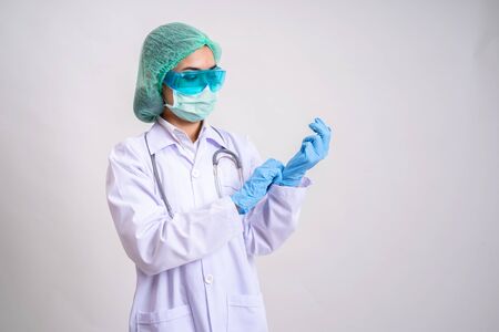 Asian female physician wear elastic hair hoods, masks, protective glasses. physician wearing glove concept, Gray isolated backgroundの写真素材