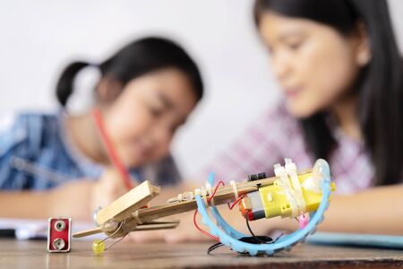A teacher and an Asian female student build a motor vehicle in a science lesson. Consultation to...