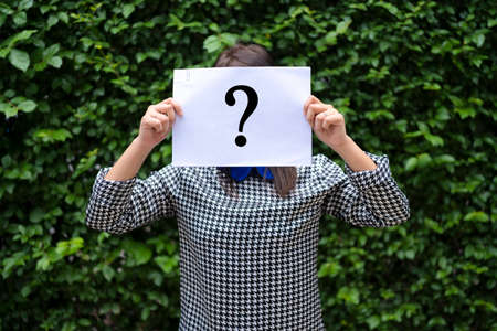 Asian Woman Holding Paper With Question Mark, The background is a leaf wall.の写真素材