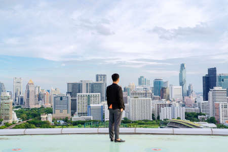 Businessman standing on building. City background with copy space. Success and vision conceptの写真素材