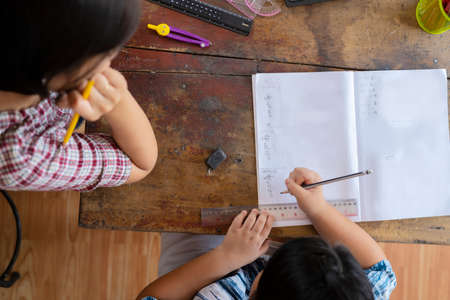 Students are solving mathematical problems concept. The teacher is teaching an Asian girl, They are...