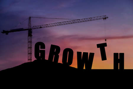 The crane is lifting the letters T to be arranged in complete order. The Growth of the construction silhouette conceptの写真素材
