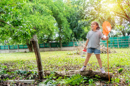 An Asian girl, she is adventuring in a wide world. Along with a bug catcher, Stand on a Timber and ready to catch insectsの写真素材
