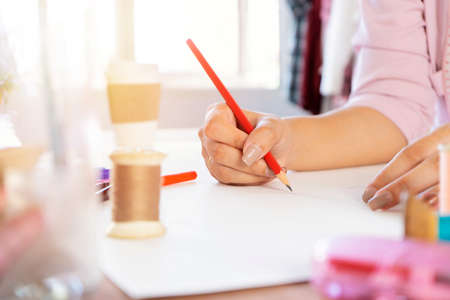 Asian women designers are using pencils to design works on paper, The sewing device is placed as an element.の写真素材