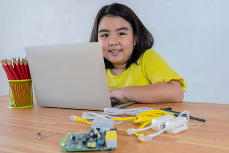 An Asian girl uses a laptop to install a robot controller from a plastic brick. Origins of education for children. STEM Education for kids.の写真素材