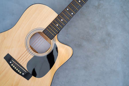 Acoustic guitar on polished cement floor, The guitar body pattern is wood grainの写真素材
