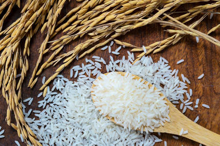 Wooden bowl with rice on rice and rice ears background with copy space for your text, top view....