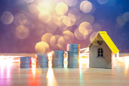 Mini house on stack of coins, Concept of Investment property, Investment risk and uncertainty in the...