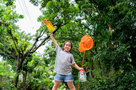 An Asian girl, she is adventuring in a wide world. Along with a bug catcher, Stand on a hill and ready to catch insectsの写真素材