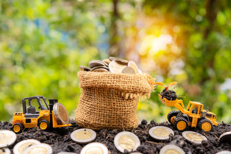 Concepts of financial business investment. A sack of bags filled with coins filled out on the mound and a crane model was loading and seedlings.の写真素材