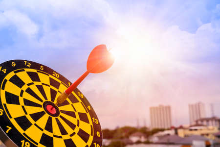 Red dart arrow hit in the target center of dartboard with sky background, Target hit in the center by arrowsの写真素材