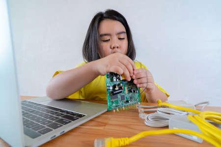 STEM Education for kids. An Asian girl uses a laptop to install a Circuit board. Origins of education for children.の写真素材