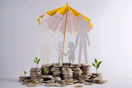 Stack of coins with family with protective umbrella on dark background, business idea and savings insurance concept.の写真素材