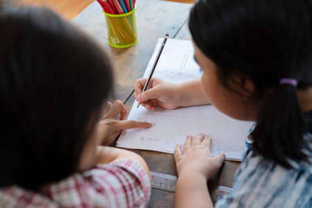 The teacher is teaching an Asian girl, learning math. Students are solving mathematical problems.