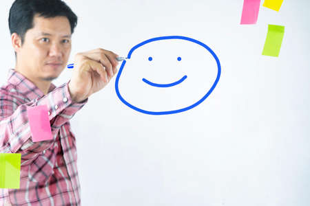 An Asian man draws a happy smile on the mirror. Represents a happy moodの写真素材