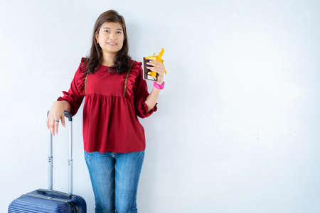 Female traveler holding passport, airplane model, suitcase on gray isolated background.の写真素材