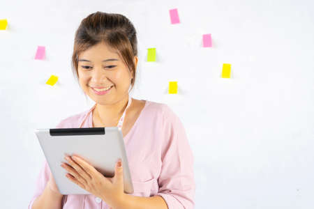 Asian female designers holding gadget in hands using  internet in Living room with interior. Electronic wireless device conceptの写真素材