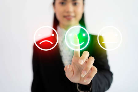 Woman pressing happy smiley face emoticon on virtual touch screen. Customer service evaluation and rating concept.の写真素材