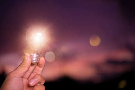 concept power energy in nature. hand holding lightbulb with solar, sunset power conceptの写真素材