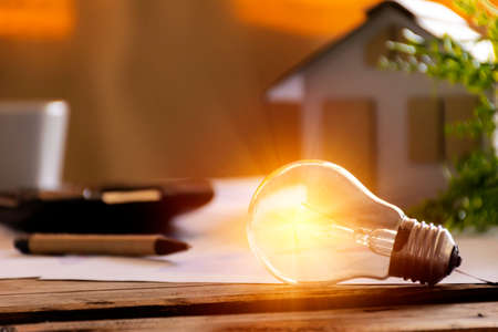 Light bulb with paper house on the table, a symbol for construction, Creative light bulb idea, power energy or business idea concept ecology, loan, mortgage, property or home.の写真素材
