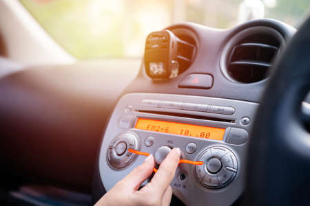 Women turning button on car radio for listening to musicの写真素材