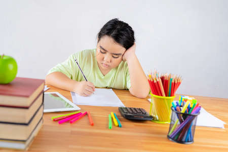 Student sits at a table with books preparing for exams. Education, home studying concept.の写真素材