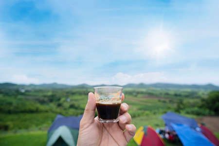 Man holding espresso coffee cup Looking at the beautiful natural mountain views. Drink coffee in the morningの写真素材