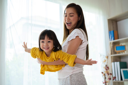 Asian family smiling and happy. Child pilot dreams of traveling, mother and daughter play together.の写真素材