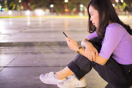 A lovely Asian woman reads a book in the university library to relax and educate herself. A large book on a wooden tableの写真素材