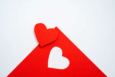 A red card is placed on a white cardstock, cut into a heart shape, communicating on Valentine's Day.の写真素材