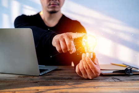 A businessman holding a light bulb in his hand demonstrates the broad vision and concept of building...