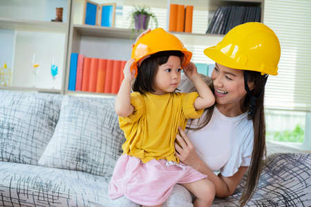 An Asian mother and daughter play as an engineer in command, with yellow helmet as role-playing equipment.の写真素材