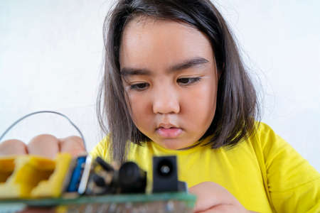 Asian women are learning simple electrical circuits. By learning from the laptop to find information about how to manually connect the circuit.の写真素材