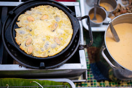 Fried mussel pancakes, Cooking mussel fried in egg batter on iron pan. Street food of Thailand.の写真素材