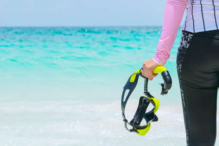 Women tourists holding diving equipment stands on a tropical beach ready to enter the water. Sea travel in Thailand conceptの写真素材