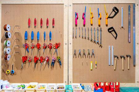 Workshop scene. Tools on the table and board. Glue, tape measure, steel ruler, screwdriver, wrench, yarn, scissors, hammer, cutter, orderly hanging, ready to use.の写真素材