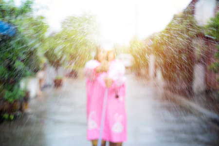 Blur background of Asian child playing with water hose outdoors on a hot sunny summer day