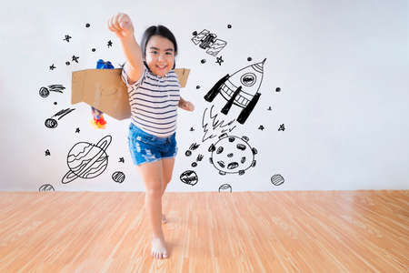 Child plays in an astronaut costume and dreams of becoming a spaceman. The background is a wall with a picture of a country.の写真素材