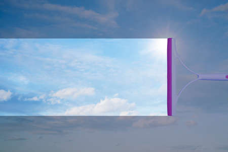 Window cleaner cleaning window with squeegee and wiper on a sunny day with a bright blue sky.の写真素材