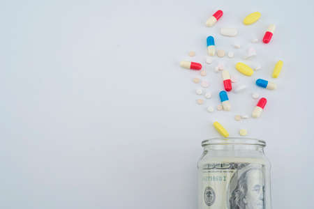 Dollar bills in a medicine box on a gray background. The medicine that is poured out of the bottleの写真素材