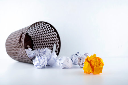 Crumpled paper in the trash can, white crumpled paper ball and different orange crumpled paper ball on a white backgroundの写真素材